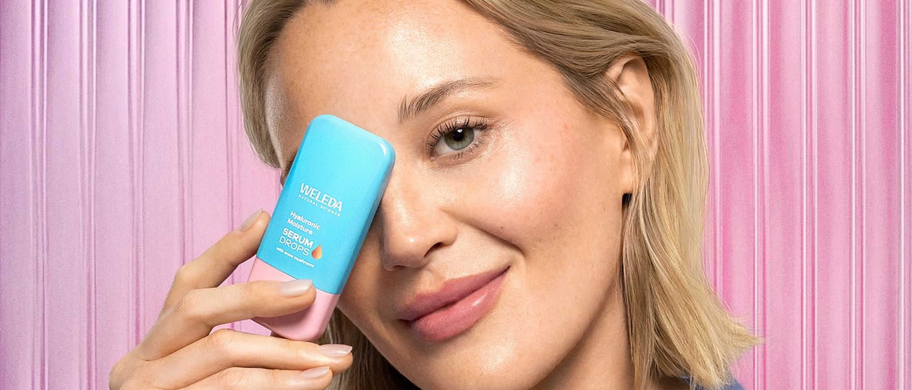 Modelul ține Hyaluronic Serum în fața feței.